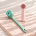 Bath and Glow Set: mint electric body brush and pink silicone facial cleansing brush on pale rose stone